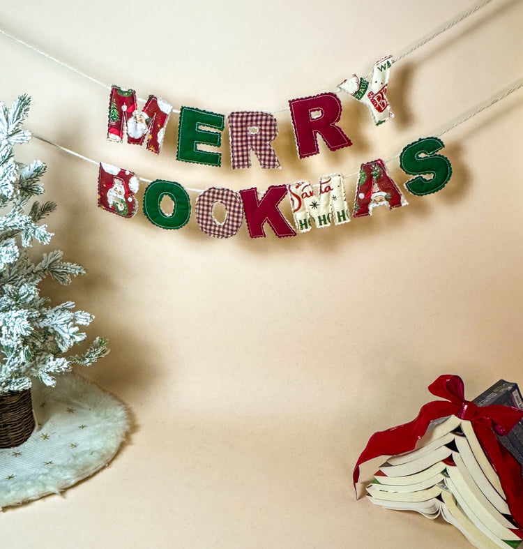Decorative banner with 'Merry Bookmas' text next to a small Christmas tree and books on a beige background