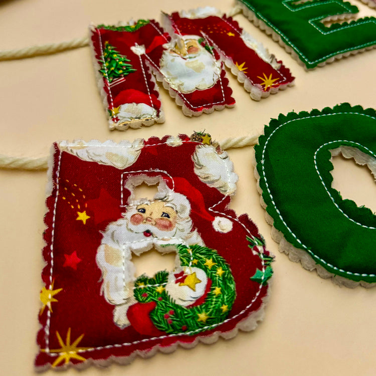 Close up of red Santa print letter on the Merry Bookmas fabric banner showing stitching details.