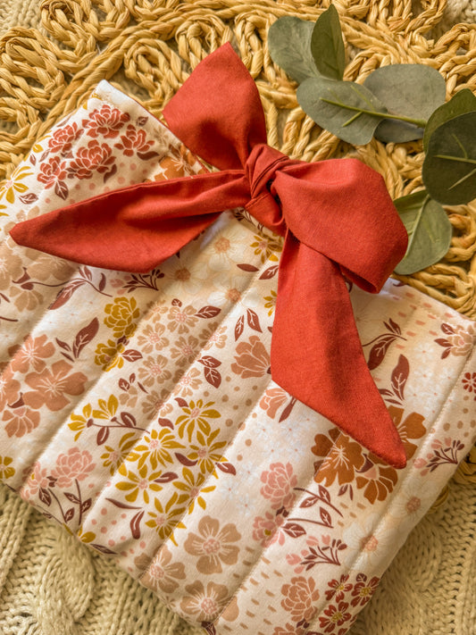 Packaged product with floral pattern and red ribbon on a textured surface