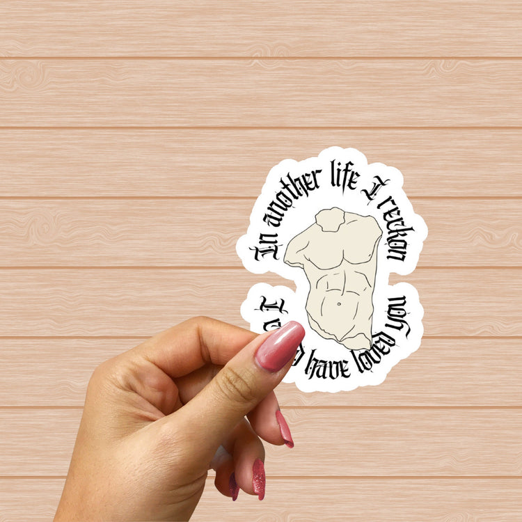 Close-up of sticker design held by fingers with soft pastel background.