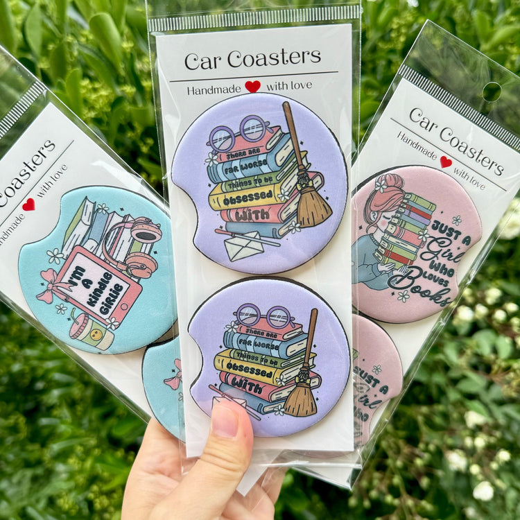 Three packs of book-themed car coasters on green outdoor background