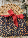 Floral-patterned fabric with a red ribbon on a textured surface