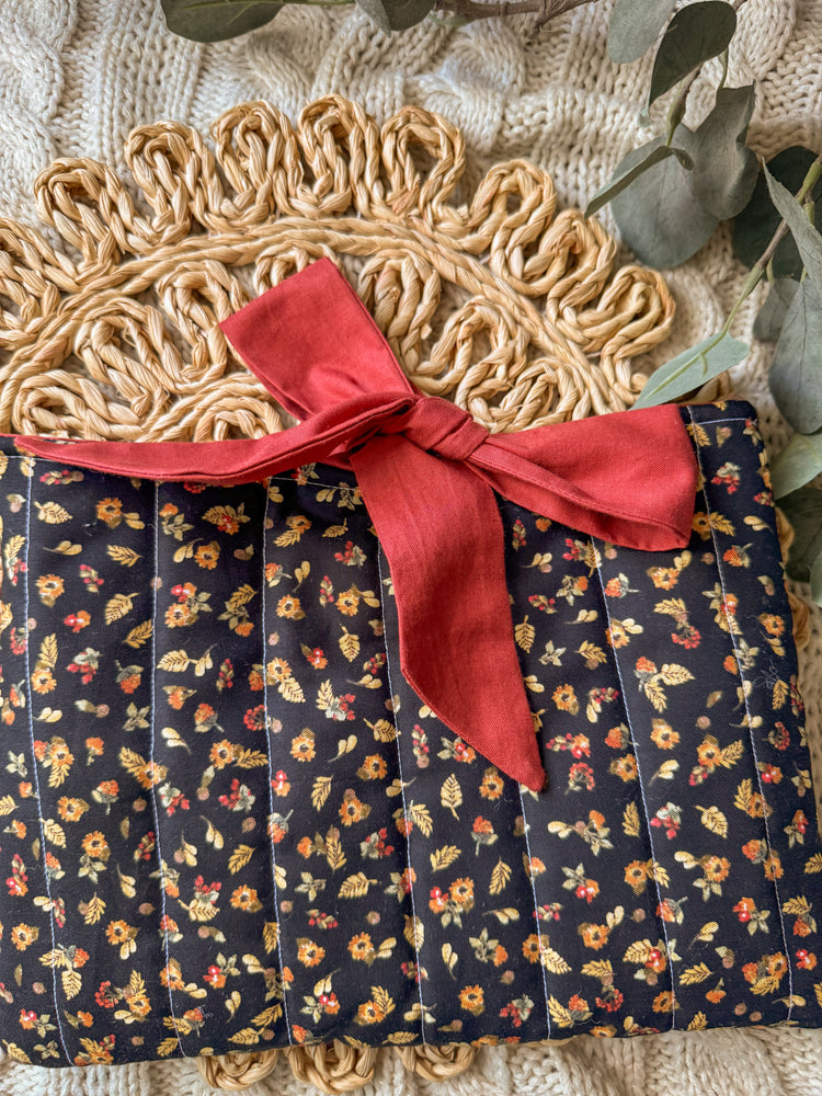 Floral-patterned fabric with a red ribbon on a textured surface