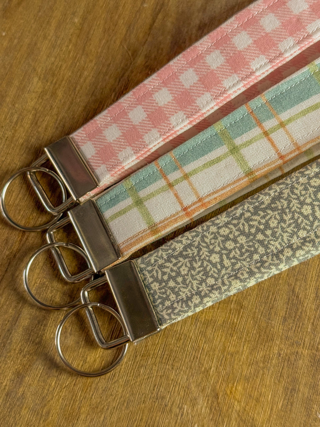 Three fabric keychains with different patterns on a wooden surface