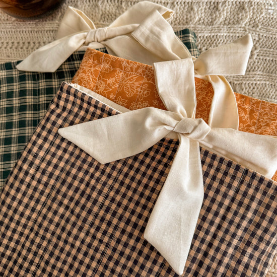 Cozy quilted book sleeves in green, brown, and orange with bow tie closures