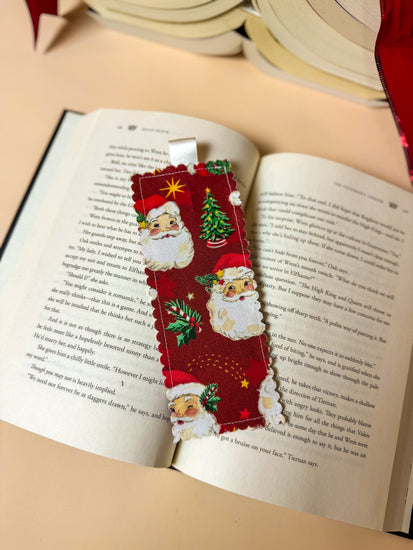 Christmas-themed bookmark with Santa Claus and trees on an open book
