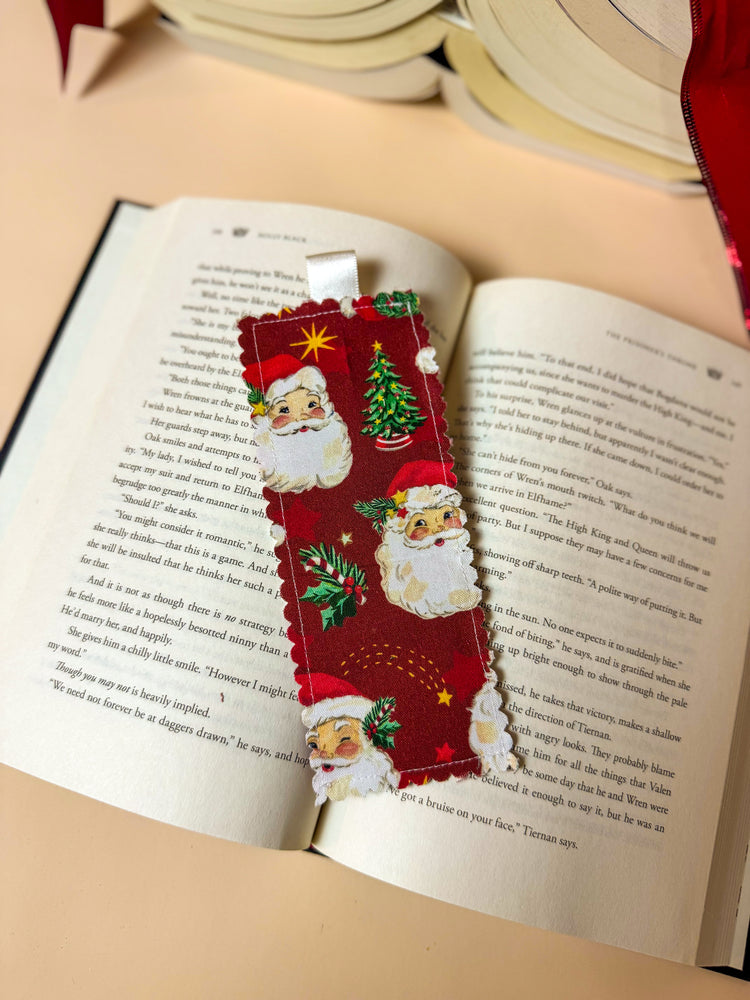 Christmas-themed bookmark with Santa Claus and trees on an open book