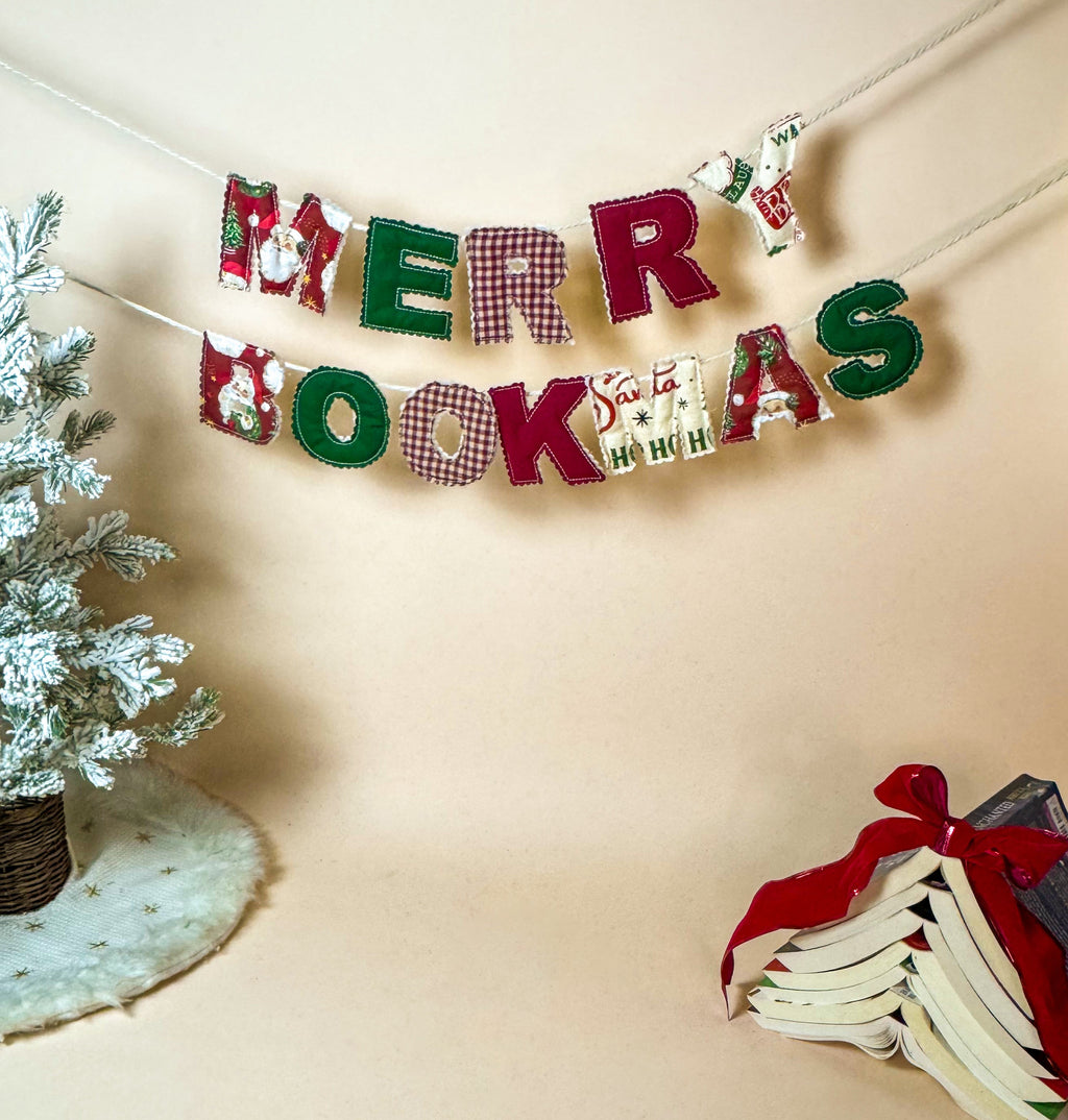 Decorative banner with 'Merry Bookmas' text next to a small Christmas tree and books on a beige background