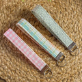 Three fabric keychains with different patterns on a woven surface
