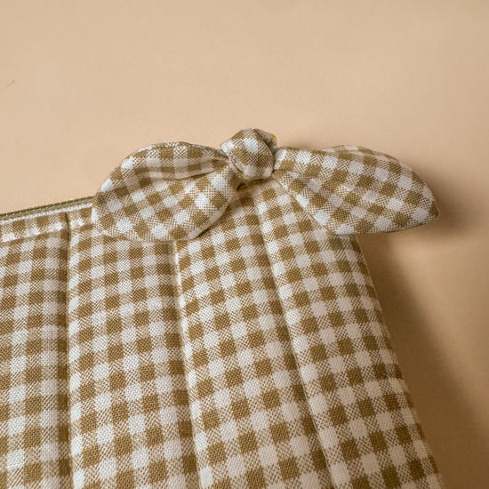 Checkered kindle sleeve with a bow detail on a beige background
