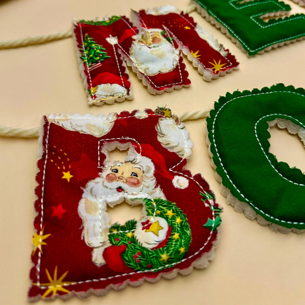 Close up of red Santa print letter on the Merry Bookmas fabric banner showing stitching details.