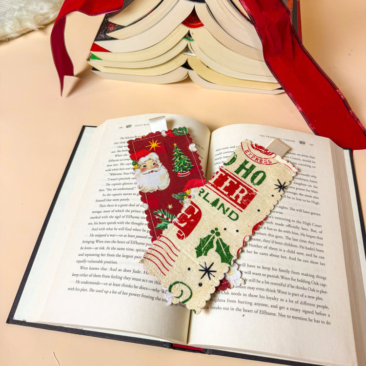 Two Christmas-themed bookmarks on an open book with a red ribbon.