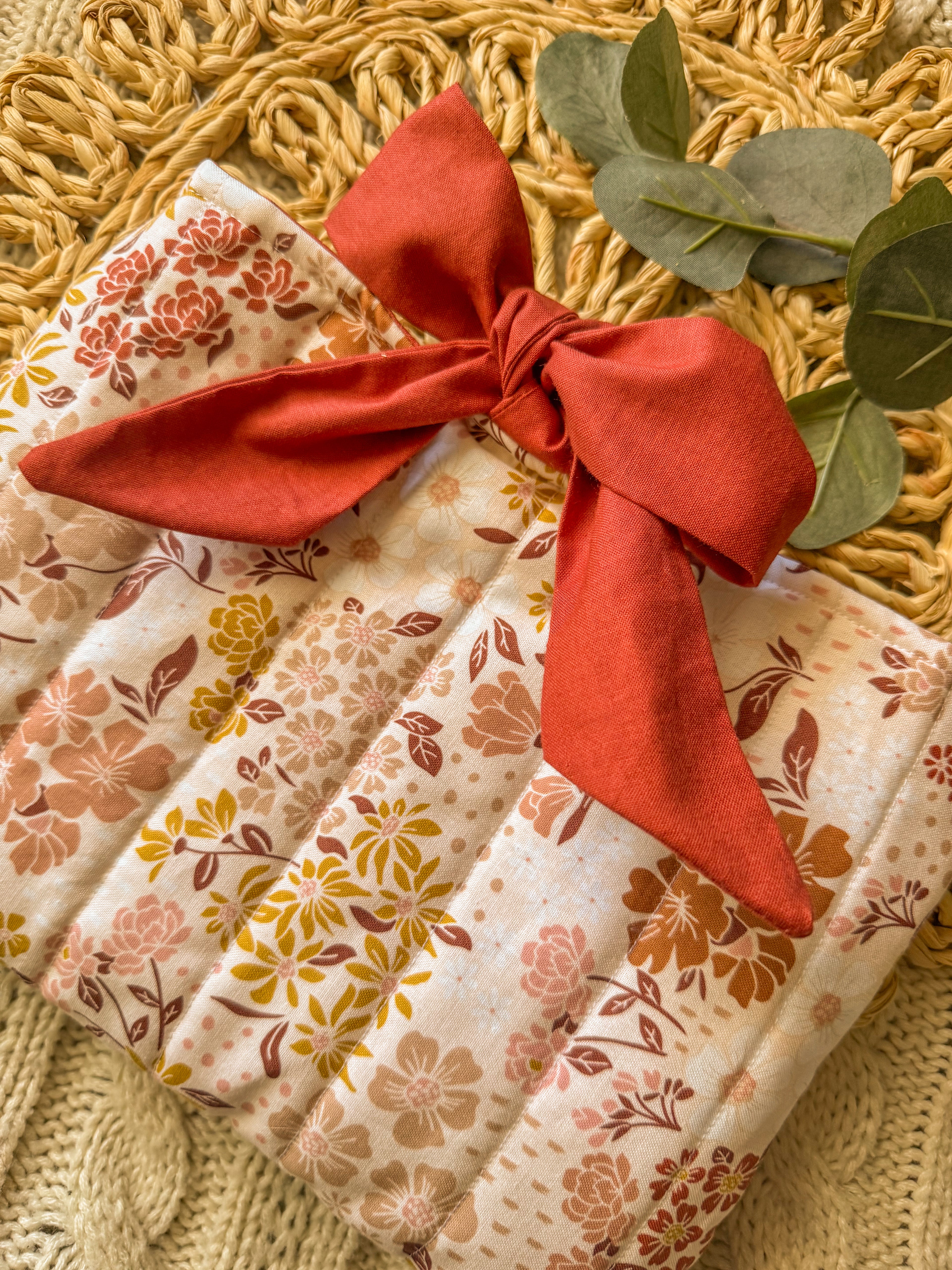 Packaged product with floral pattern and red ribbon on a textured surface