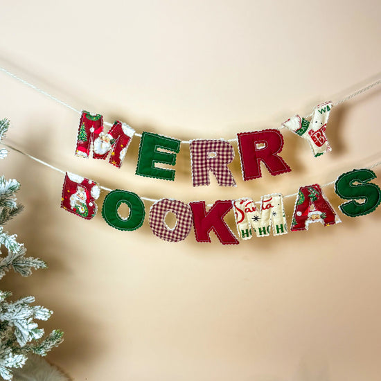 Simple clean shot of the Merry Bookmas banner hanging with a frosted Christmas tree beside it.
