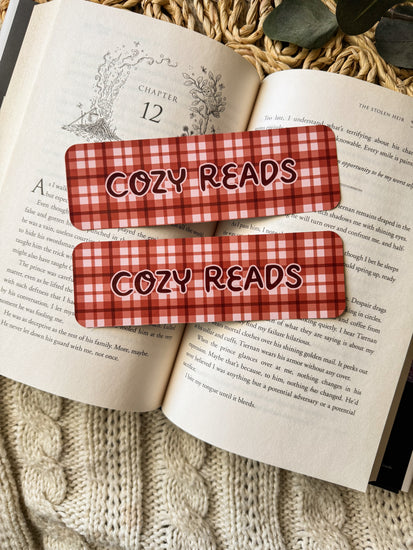 Two maroon and white checkered bookmarks with 'Cozy Reads' text on an open book.