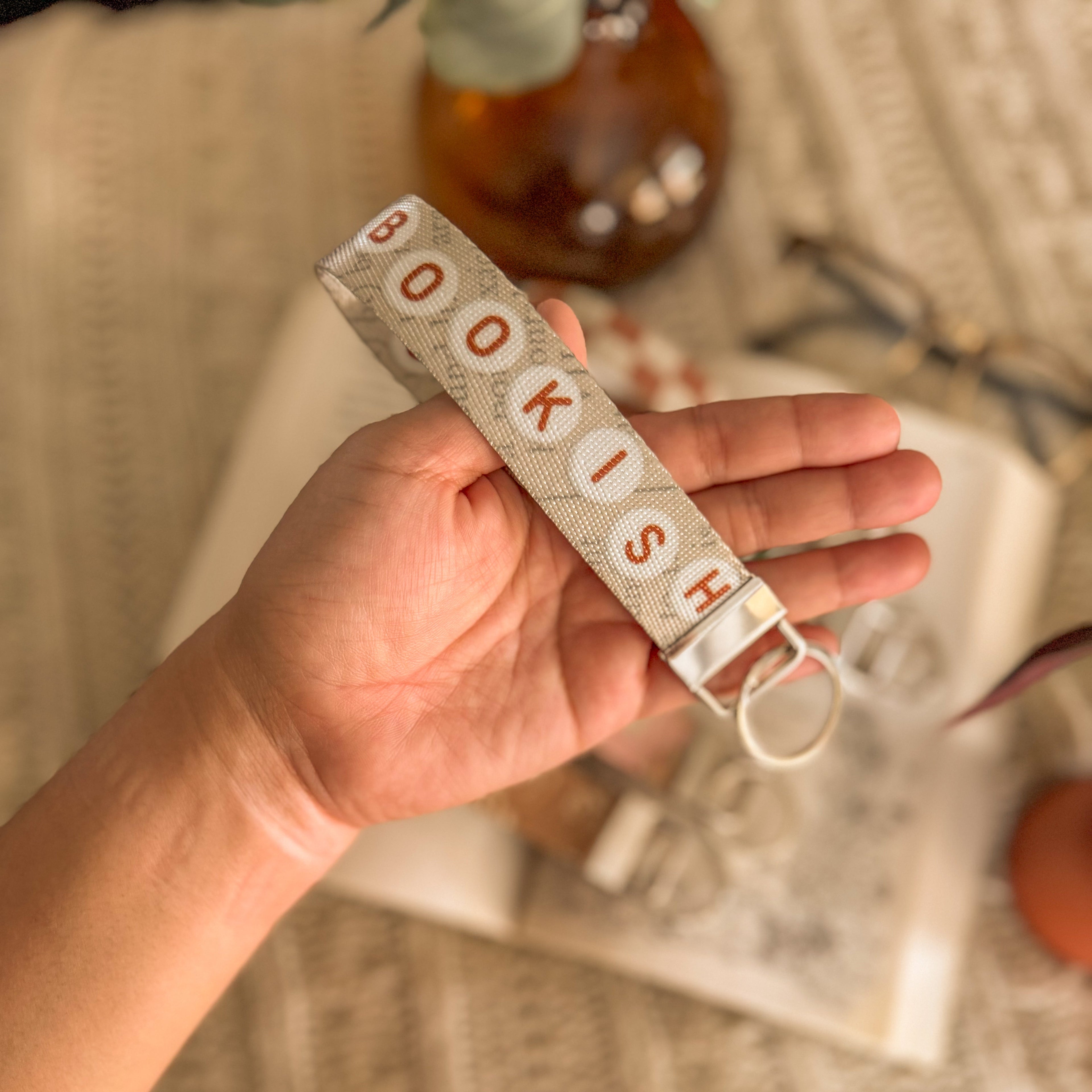 Hand holding bookish key fob, bookish is spelled in alphabet friendship bracelet beads