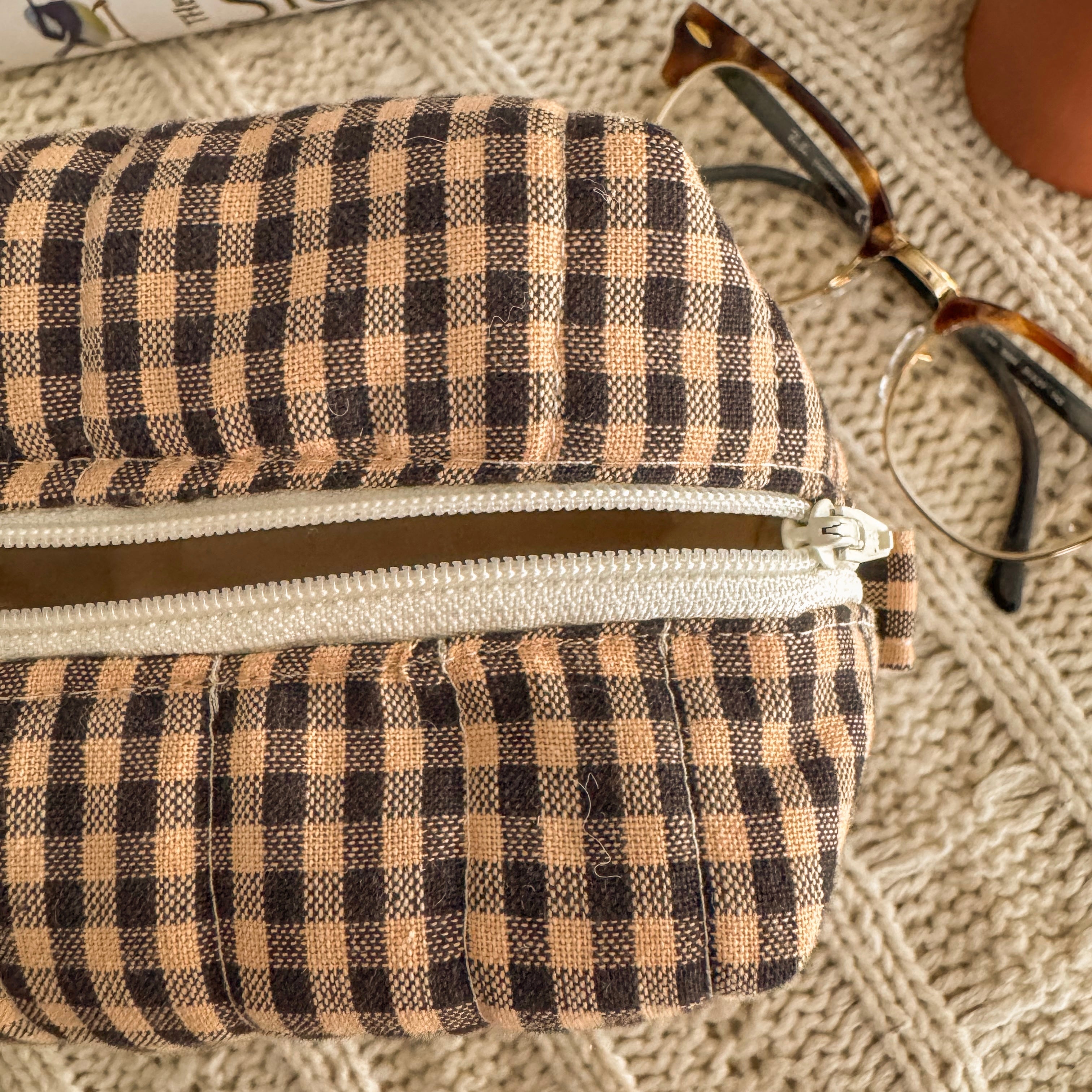 Close up of brown quilted zipper box highlight the boxy shape, cream lining and cream zipper 