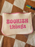 Cream canvas pouch with pink “Bookish Things” text lying on checkered blanket