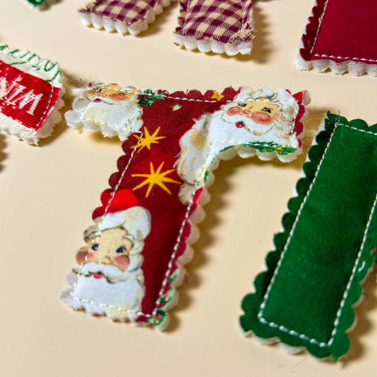 Close up of fabric letters on the Merry Christmas banner showing stitching and texture.