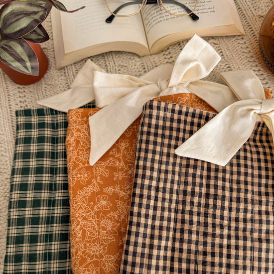 Side by Side view of green, brown, and yellow quilted book sleeves with cream bow closures