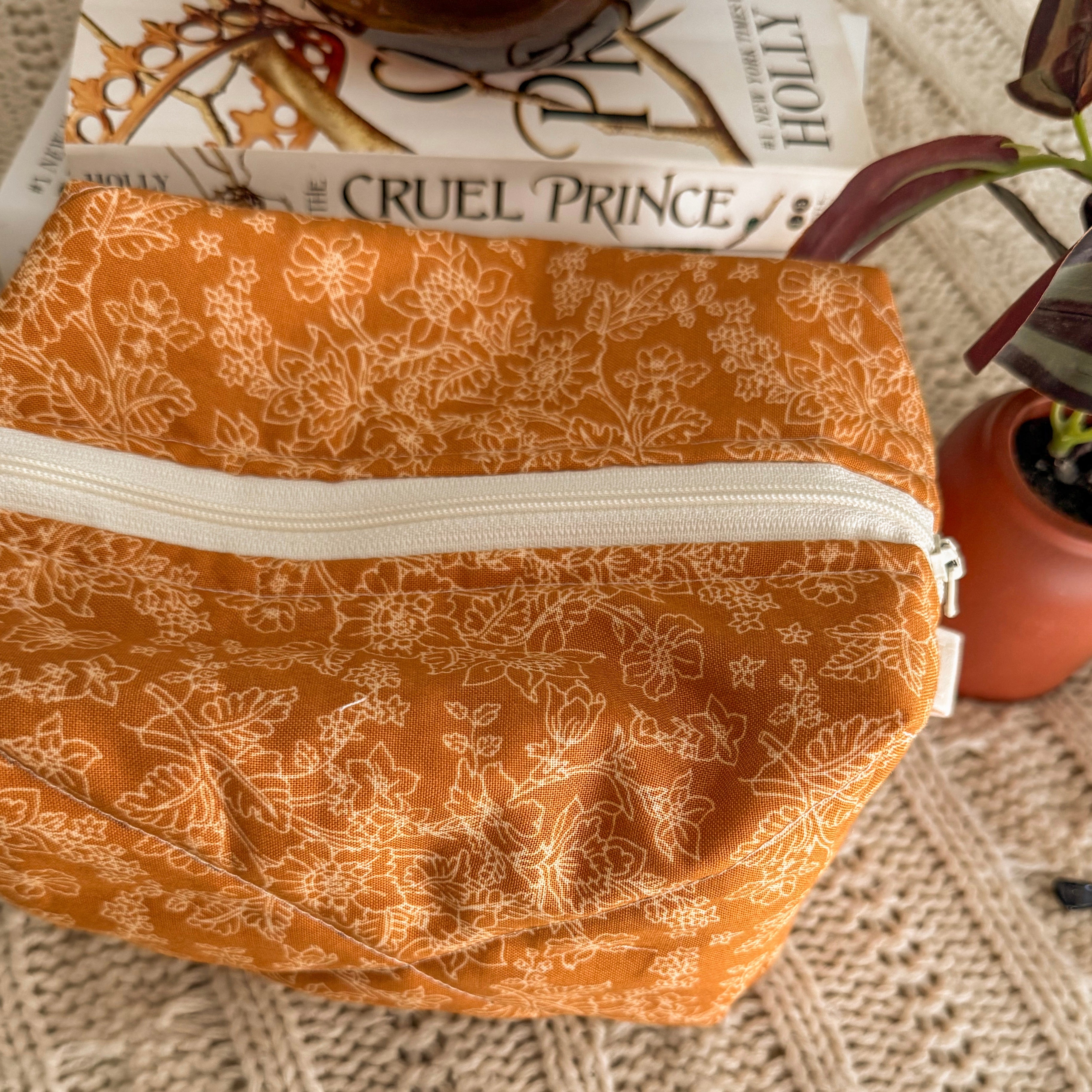 Close up of warm yellow floral quilted zipper pouch with white zipper and white tabs