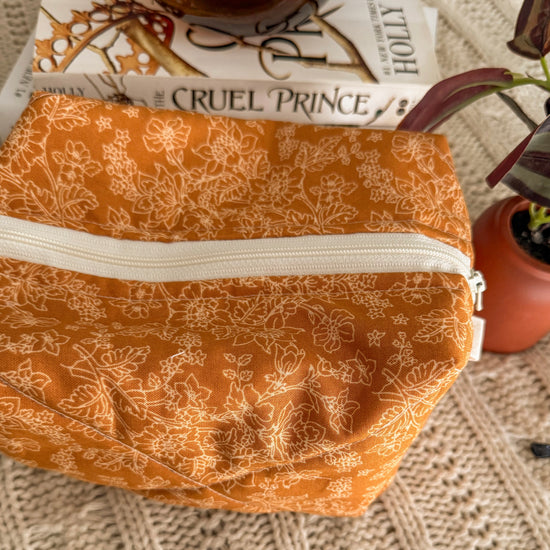 Close up of warm yellow floral quilted zipper pouch with white zipper and white tabs