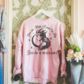 Pink A Fate Inked in Blood sweatshirt by Dex Avenue, featuring the quote 'You Are Mine Born-In-Fire' and a moon graphic, displayed on a hanger against floral wallpaper