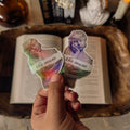 A holographic "From the Collection of a Bibliophile" sticker placed on a vintage book. The scene is styled with a white marble classical bust statue and a lit taper candle, creating a serene Light Academia aesthetic.