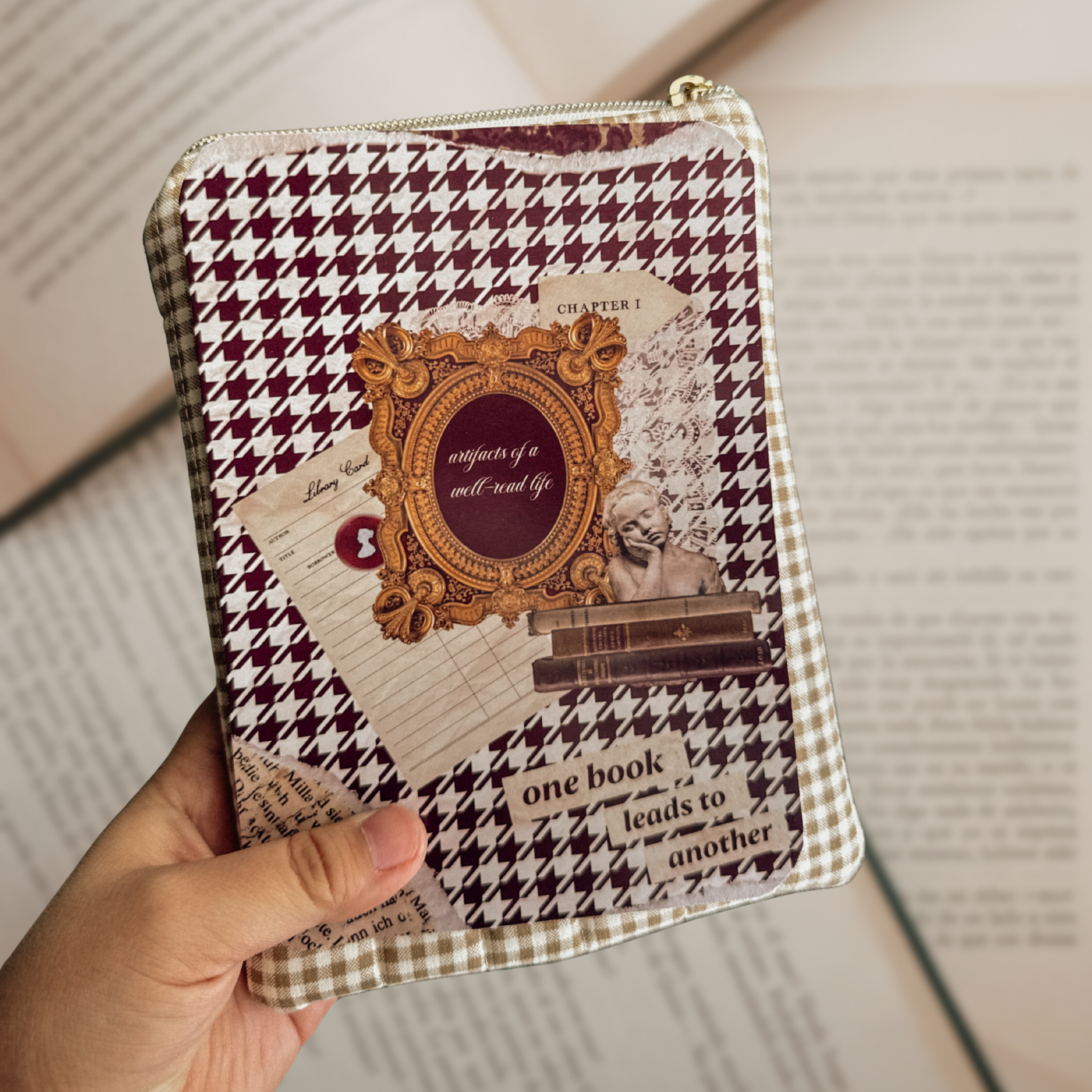 Dark Academia Kindle insert with a maroon houndstooth pattern and vintage frame collage, shown tucked into a neutral checkered book sleeve over an open book.