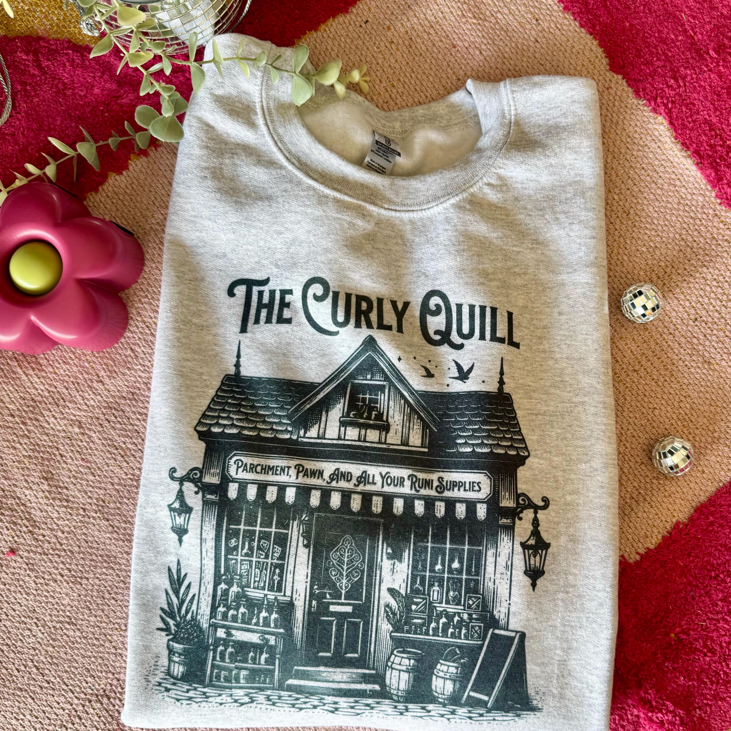 Ash grey When the Moon Hatched Sweatshirt by The Curly Quill, featuring a vintage-style faded print and styled with cozy books and reading props.