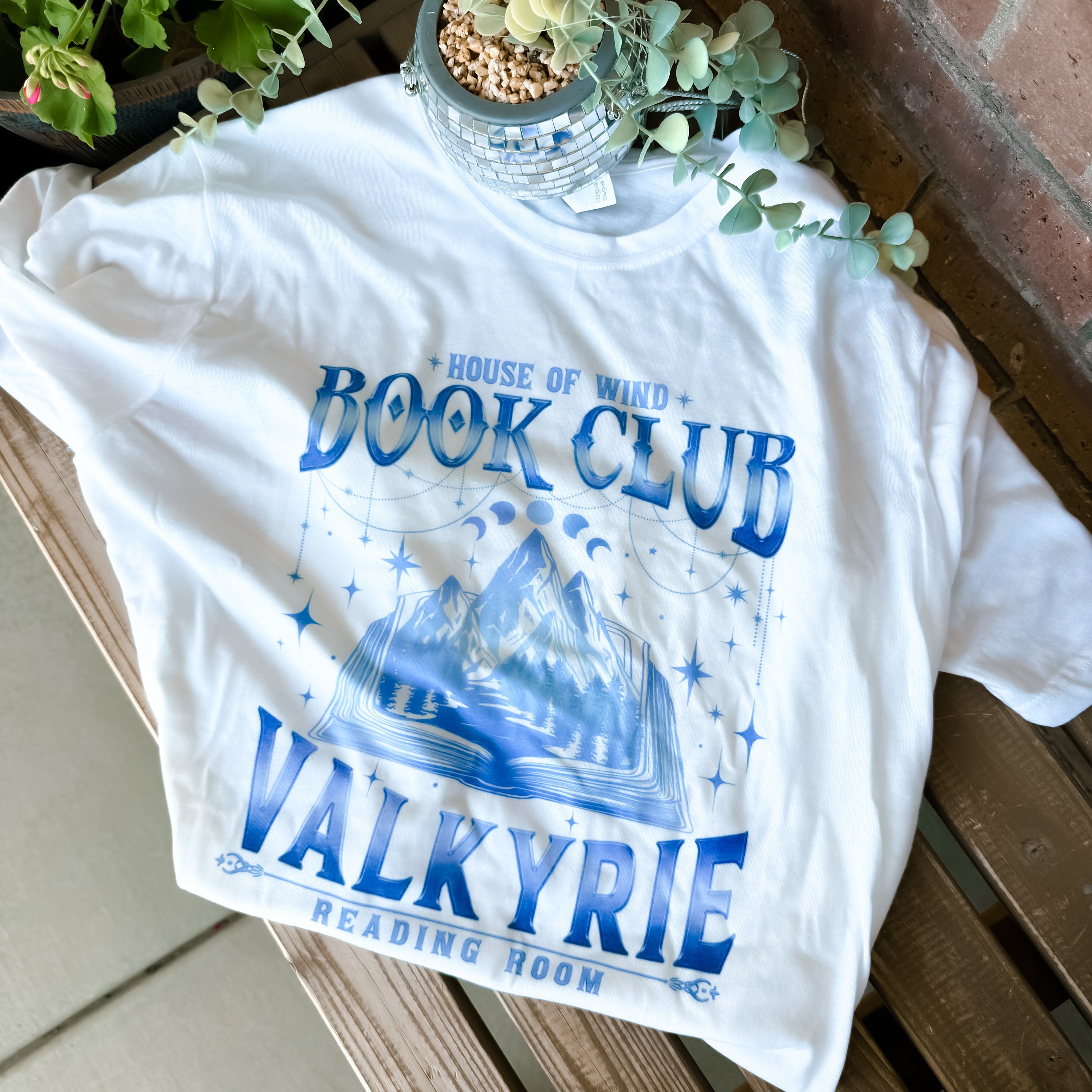 Flat lay of ACOTAR tee with cozy reading props and literary styling.