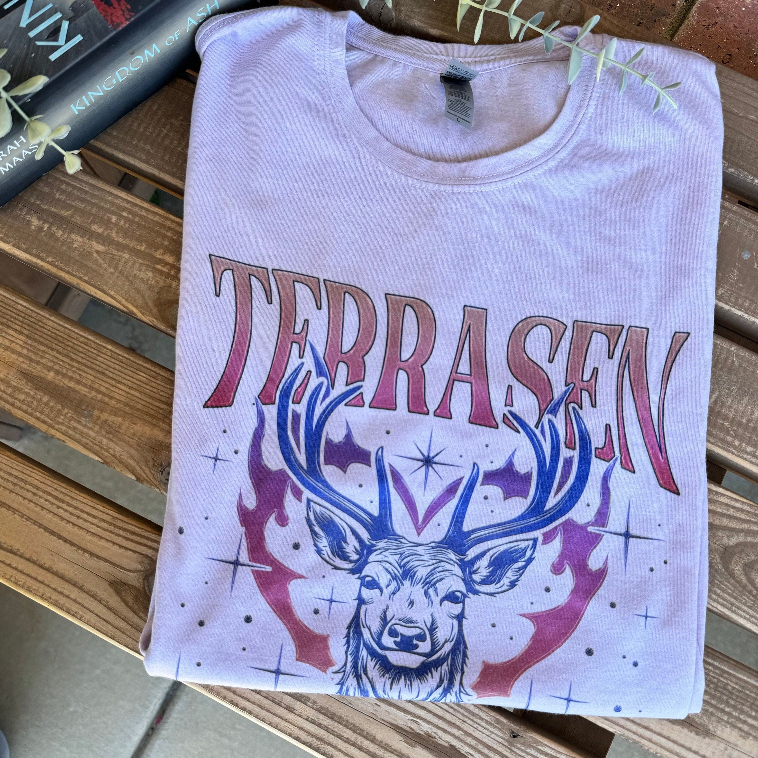 Throne of Glass Terrasen graphic tee styled with fantasy books and cozy reading props.