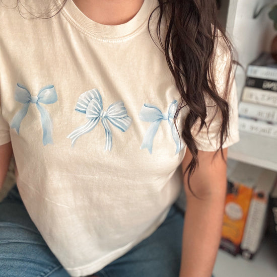 Close-up of ivory fabric showing playful blue bows design.