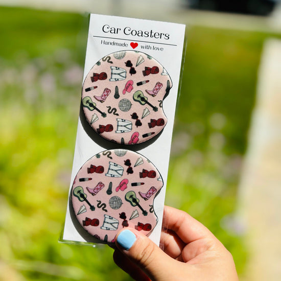 Pop culture-inspired car coasters on wooden surface with floral backdrop