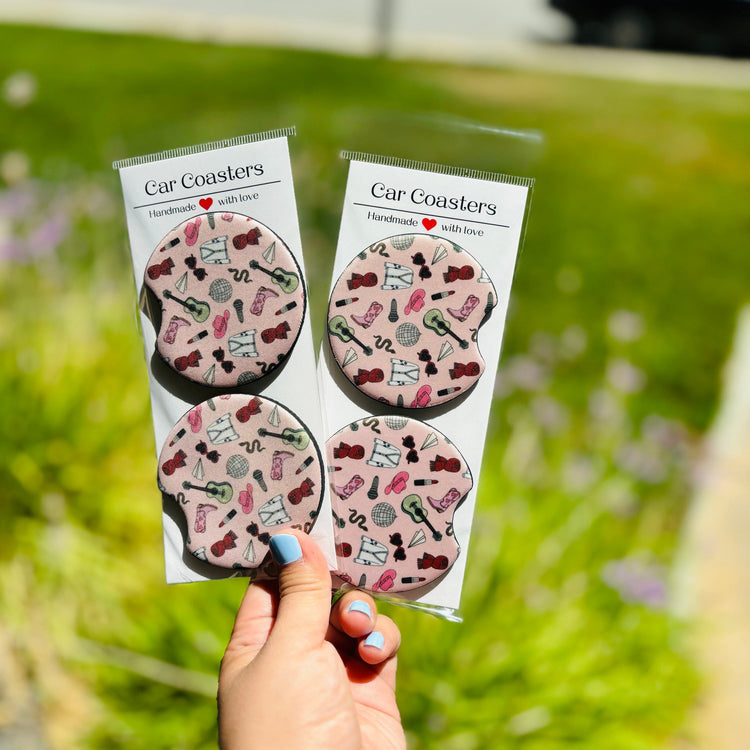 Two music-themed neoprene car coasters in clear packaging, held in hand