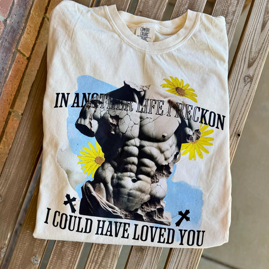 White crew neck t-shirt with text and graphic design featuring a muscular chest and flowers.