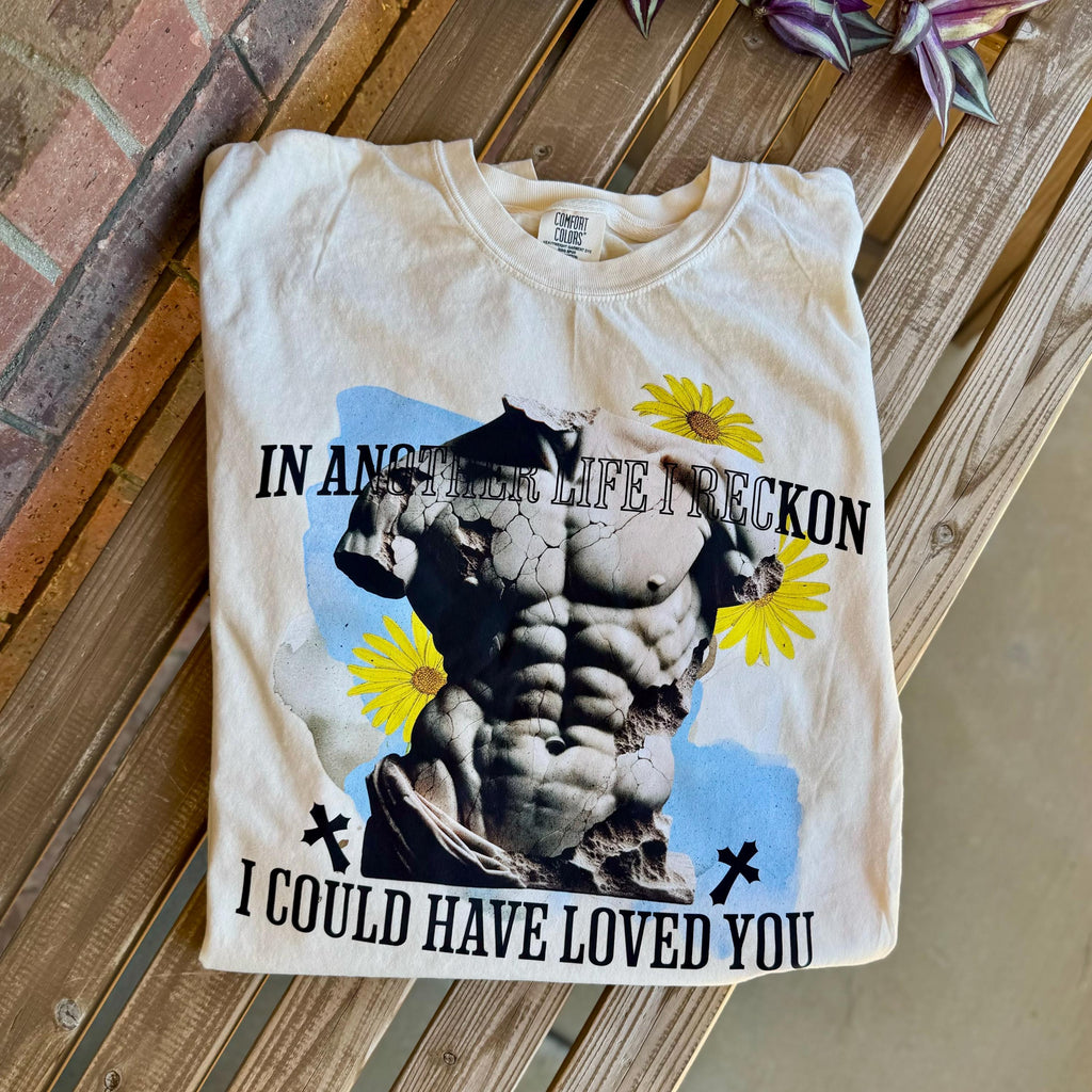 Beige Julian Haites Magnolia Parks quote tee styled with books and cozy accents.